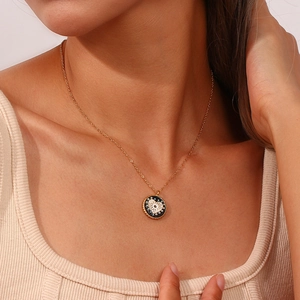 Gros plan d'un collier pendentif pièce en or avec émail noir et motif de cœur blanc