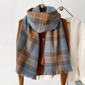 Detail of blue and orange plaid scarf with frayed edges and thick cashmere texture