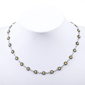Close-up of daisy charms necklace with black petals and yellow center on a white bust