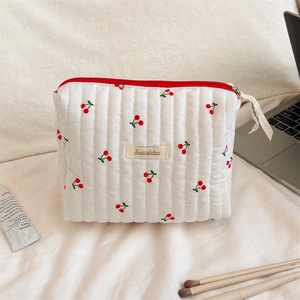 Macro shot of quilted cherry print toiletry bag with zipper and decorative ribbon detail