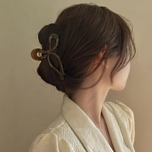 Detailed view of an amber brown resin ribbon hair claw clip worn on a high ponytail