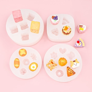 Silikonformen für Miniatur-Essen wie Käse und Kuchen auf rosa Hintergrund für DIY-Projekte