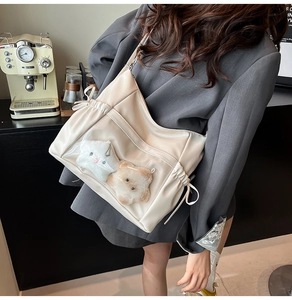Detail of cream PU leather bag with transparent PVC pocket and plush animal charms