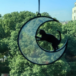 Detail of moon cat suncatcher showing translucent blue glass and black silhouette