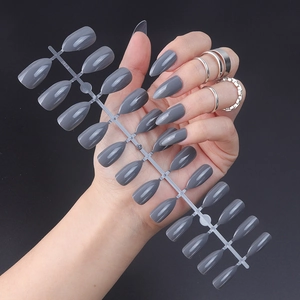 Close-up of glossy dark grey pointed stiletto press-on nails on a 24-piece display rack