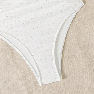 Detailed close-up of white eyelet embroidery fabric on a one-piece swimsuit