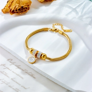 Elegant gold snake chain bracelet with sparkling rhinestone round pendant on a white tray