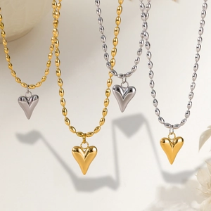 Detail of double heart pendants in gold and silver finish on a beaded titanium chain