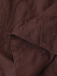 Détail d'une broderie complexe ton sur ton sur un tissu en coton marron chocolat