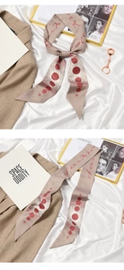Detail of beige silk twilly with red celestial patterns and fashion text on white fabric