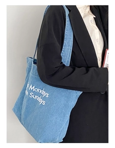 Gros plan d'un sac cabas en jean bleu avec imprimé Mondays Sundays porté par un mannequin