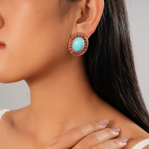 Detail of vintage bohemian earrings featuring a turquoise stone with red rhinestones