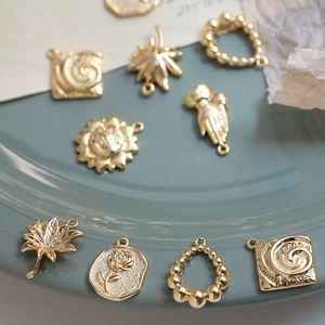 Golden sun maple leaf rose charms for jewelry making on teal ceramic plate