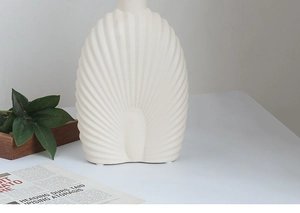 Close-up of cream ceramic vase with elegant radial shell-like ribbed texture