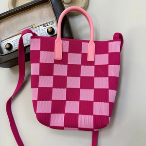 Detail of pink checkerboard knit bag showing woven texture with handle and shoulder strap
