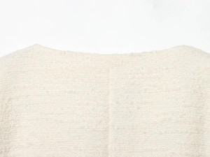 Detail van de witte tweed jas halslijn toont de textuur van de stof en stikwerk