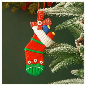 Close-up of a Christmas stocking ornament hanging on a frosted pine tree branch