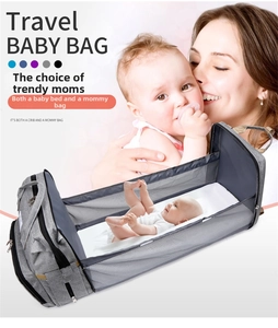 Detail of grey travel baby bag unfolding into a portable crib with a soft white mattress