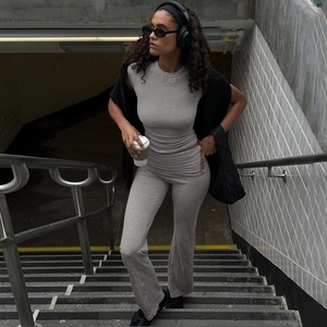 Dettaglio del set grigio con crop top aderente e pantaloni a zampa indossato da modella