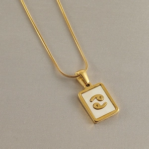 Detail view of a 18k gold plated stainless steel rectangle pendant with Cancer zodiac symbol