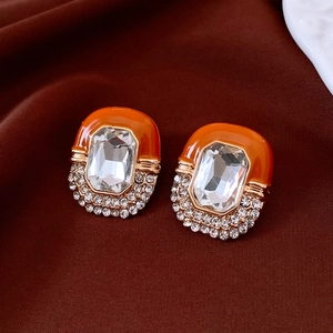 Macro shot of vintage style orange enamel earrings with crystal inlay and gold trim