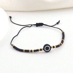 Detail of adjustable black woven bracelet with Evil Eye bead and gold accents