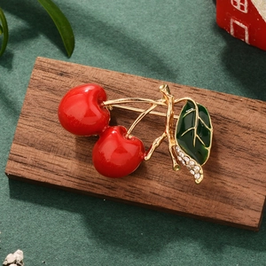Close-up of red cherry brooch with gold stem, green leaf, and sparkling rhinestones