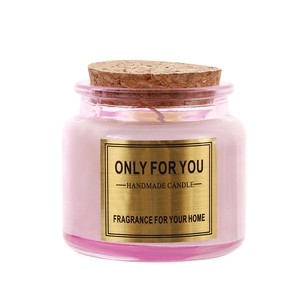 Pink glass aromatherapy candle with cork lid and gold textured label on white background