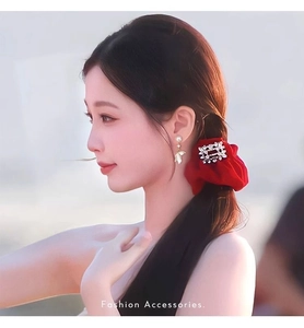 Close-up of pearl wing earrings and red velvet headband with square buckle on model