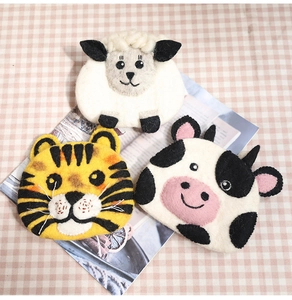 Close-up of wool felt sheep, tiger and cow shaped coin pouches on a pink cloth