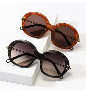 Close-up of vintage round sunglasses showing gold metal floral temple details