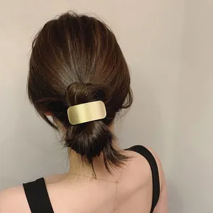 Close-up of minimalist rectangular gold metal hair clip on low bun hairstyle