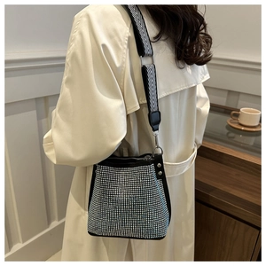 Detail of a sparkling rhinestone bucket bag with a chic black and white woven strap