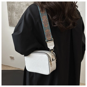 Detail showing white PU crossbody bag with embossed rose and embroidered wide strap