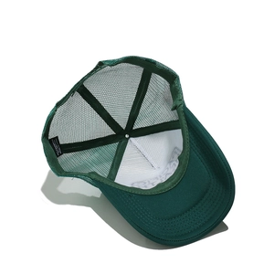 Interior detail of a dark green mesh trucker hat showing the breathable mesh and material tag
