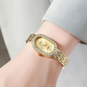 Close-up of elegant gold oval quartz watch with rhinestone bezel on a woman's wrist