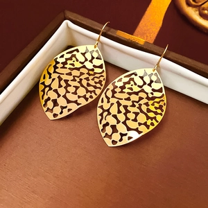 Macro detail of golden hollow leaf earrings with textured finish in a gift box