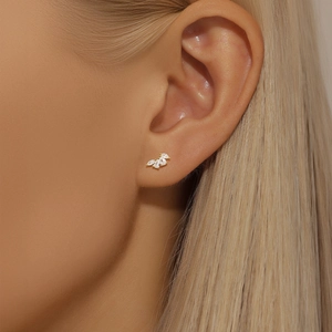 Close-up of golden marquise stud earrings with white zircon leaves worn on ear