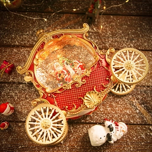 Vintage Christmas carriage music box with Santa and snow globe on a snowy background