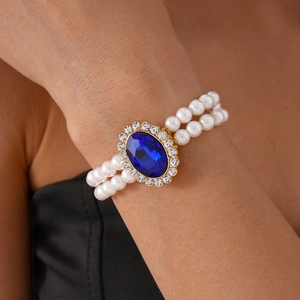Detail view of double-layer pearl bracelet with blue oval gemstone and gold finish