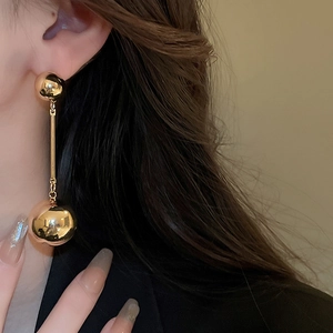 Detail showing high-quality metallic double ball drop earrings with glossy gold finish