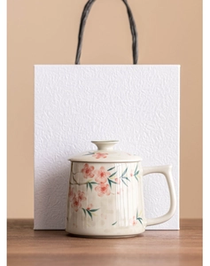 Close-up of ceramic peach blossom mug with lid and matching textured white gift bag