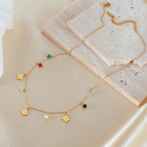 Minimalist gold stainless steel star necklace with colorful beads on silk background