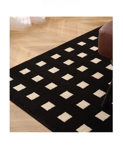 Detail of modern black and white plaid woven rug with thick knit texture on wood floor