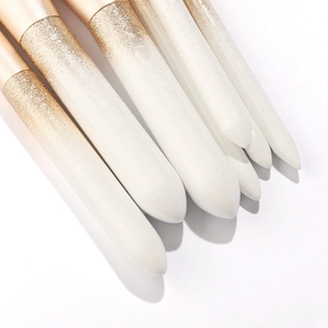 Detailed macro view of white makeup brush handles with luxury gold glitter gradient finish