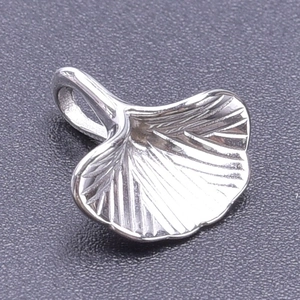 Macro shot of silver ginkgo leaf pendant in 304 stainless steel on a textured surface