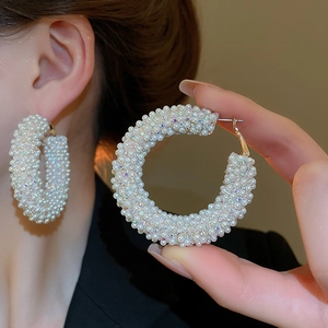 Detail of large hoop earring with shimmering white pearls and colorful rhinestones