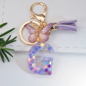 Detail of crystal resin letter G keychain with holographic purple star sequins and tassel