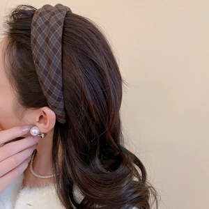 Detailed view of a brown checkered fabric headband paired with elegant pearl jewelry