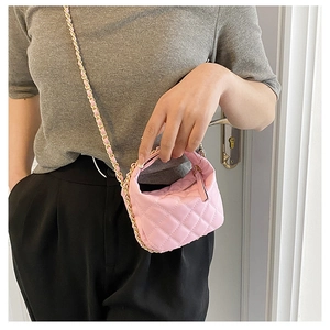 Detailed shot of a pink quilted mini bag with a woven gold chain and leather strap